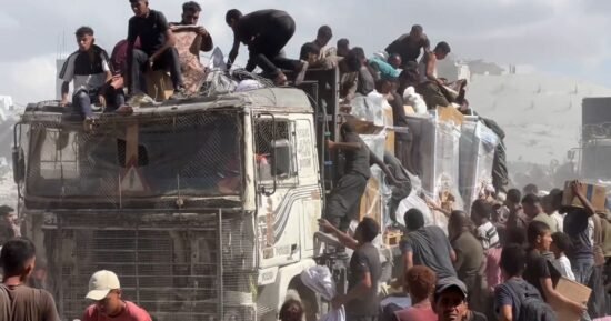 Palestinians crowd onto aid trucks moving through Gaza