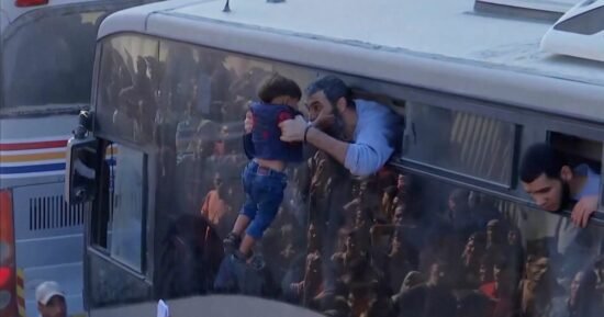 Child embraced by freed Palestinian prisoner as buses arrive in Gaza